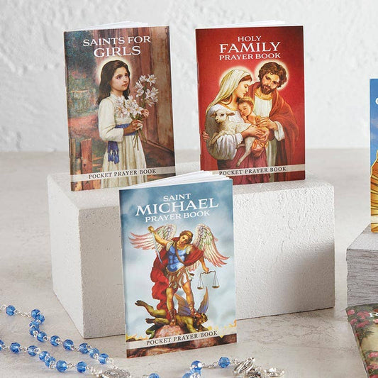 Three prayer books featuring religious illustrations on a white surface.