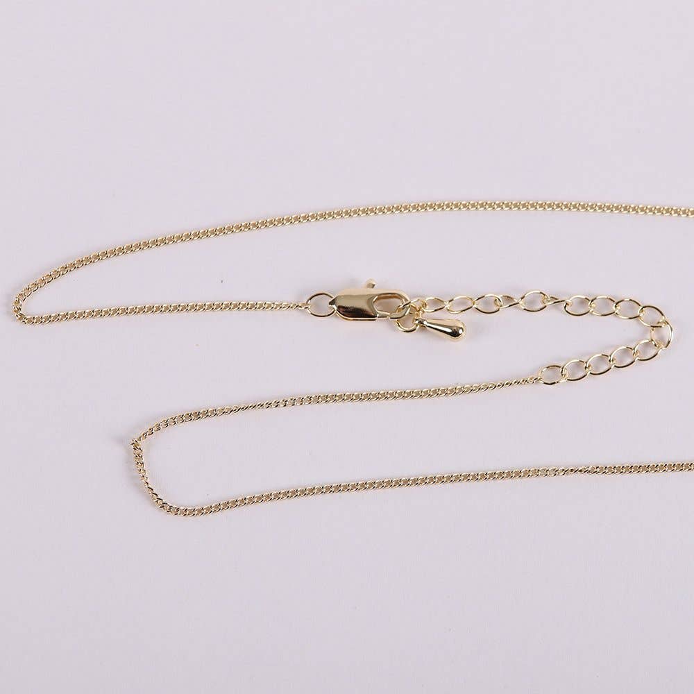 Gold chain necklace on a light gray background