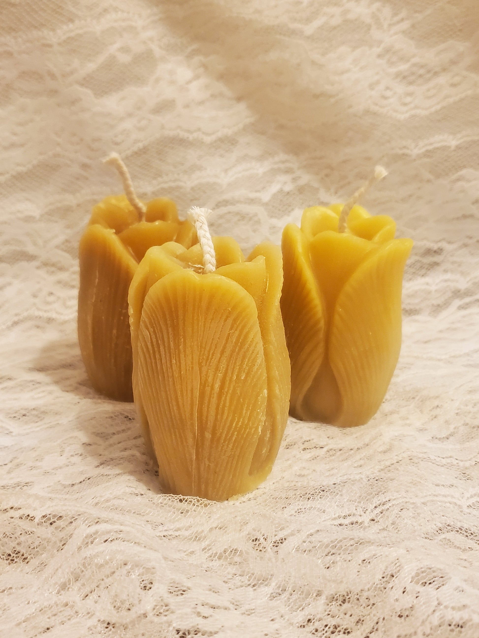 Three yellow candles on a textured beige surface