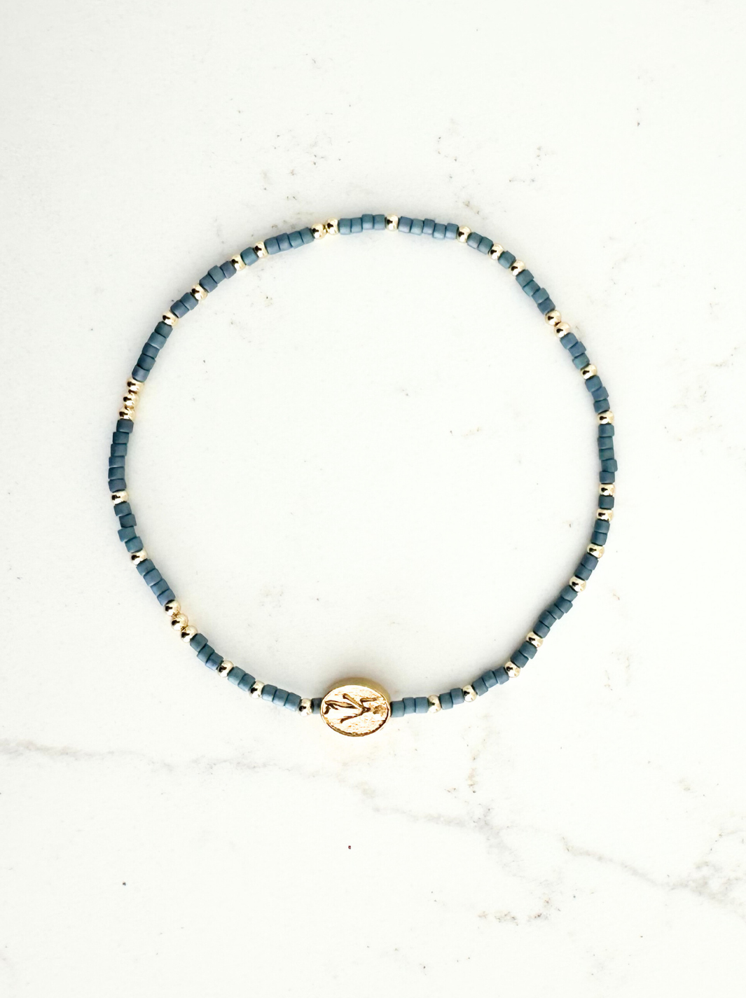 Blue beaded necklace with a gold clasp on a white marble surface