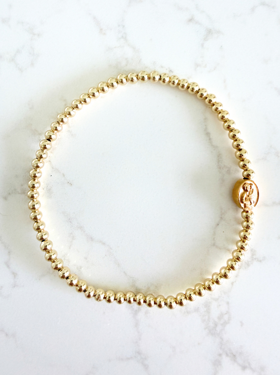 Gold beaded bracelet on a marble surface