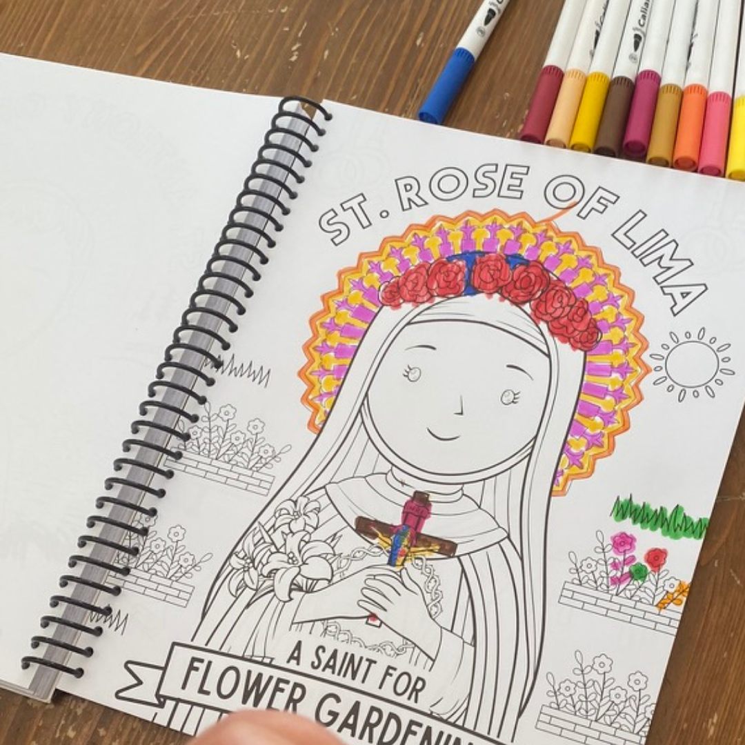 Coloring book with a saint illustration and colored markers on a wooden surface