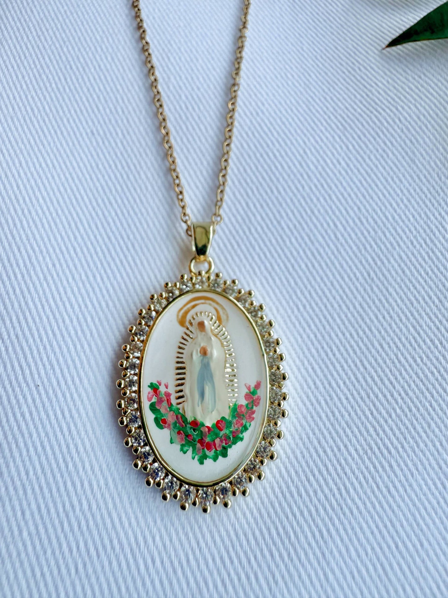 Gold necklace with a religious pendant on a light blue fabric background