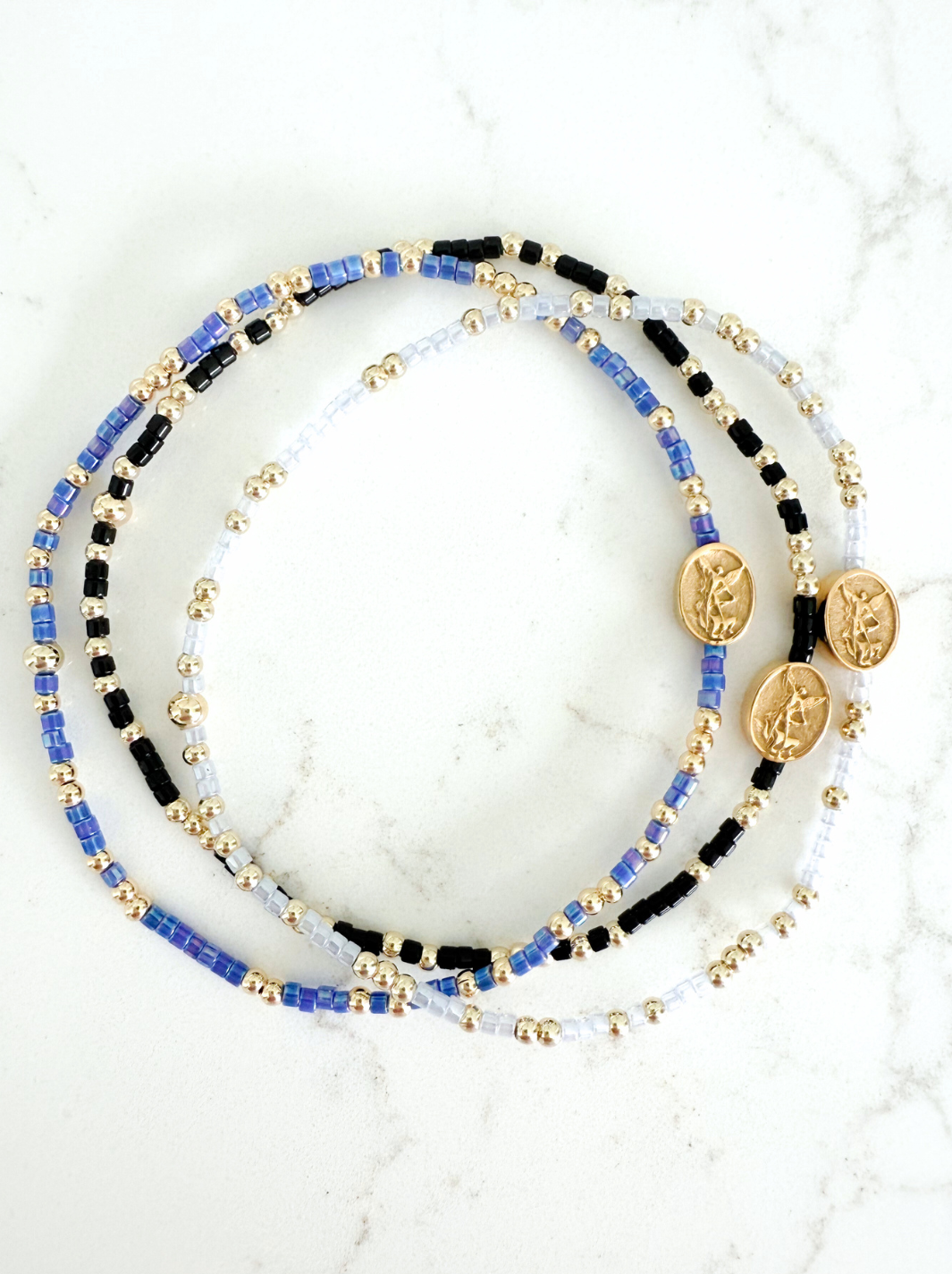 Set of beaded bracelets with coins on a marble surface