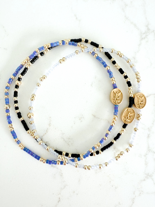 Set of beaded bracelets with coins on a marble surface