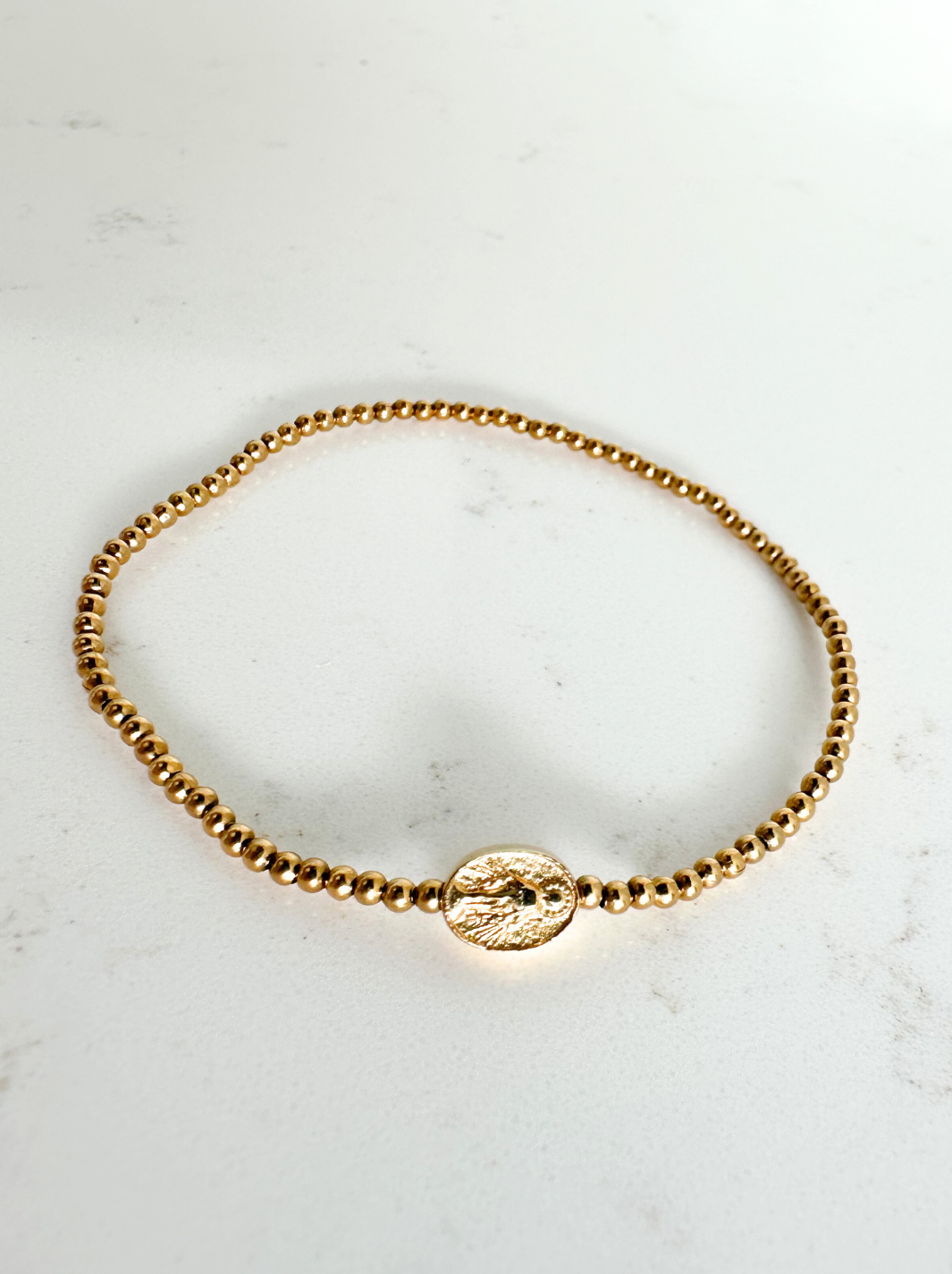 Gold bracelet on a light marble background