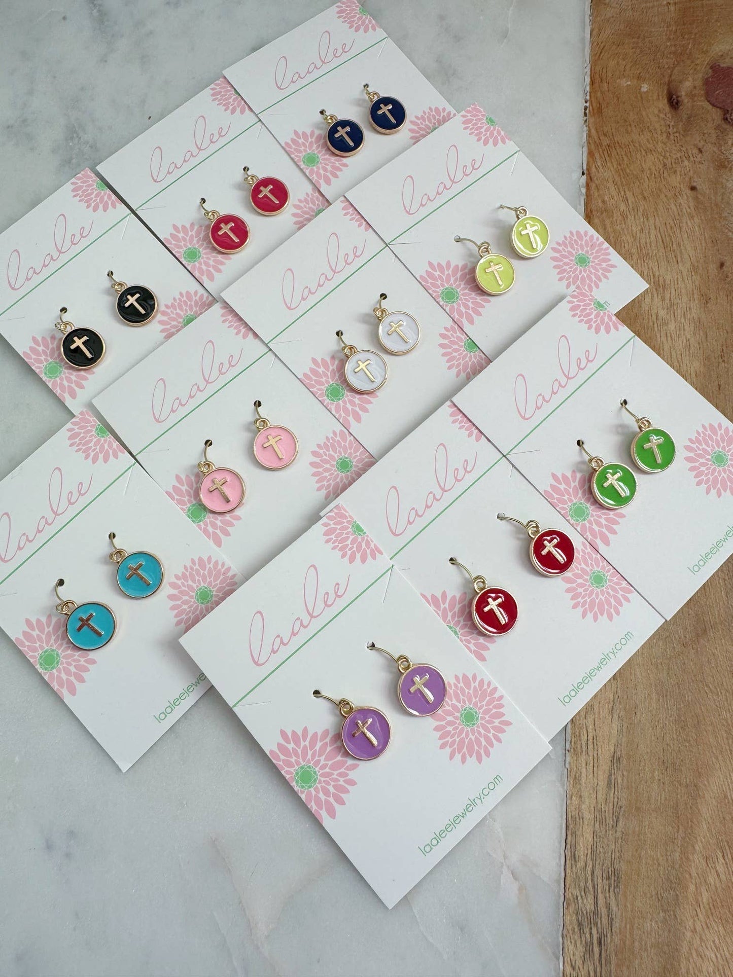 Set of earrings on branded cards with a floral design on a marble surface.