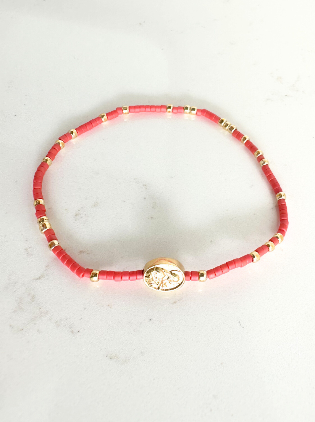 Red beaded bracelet with gold accents on a light gray background