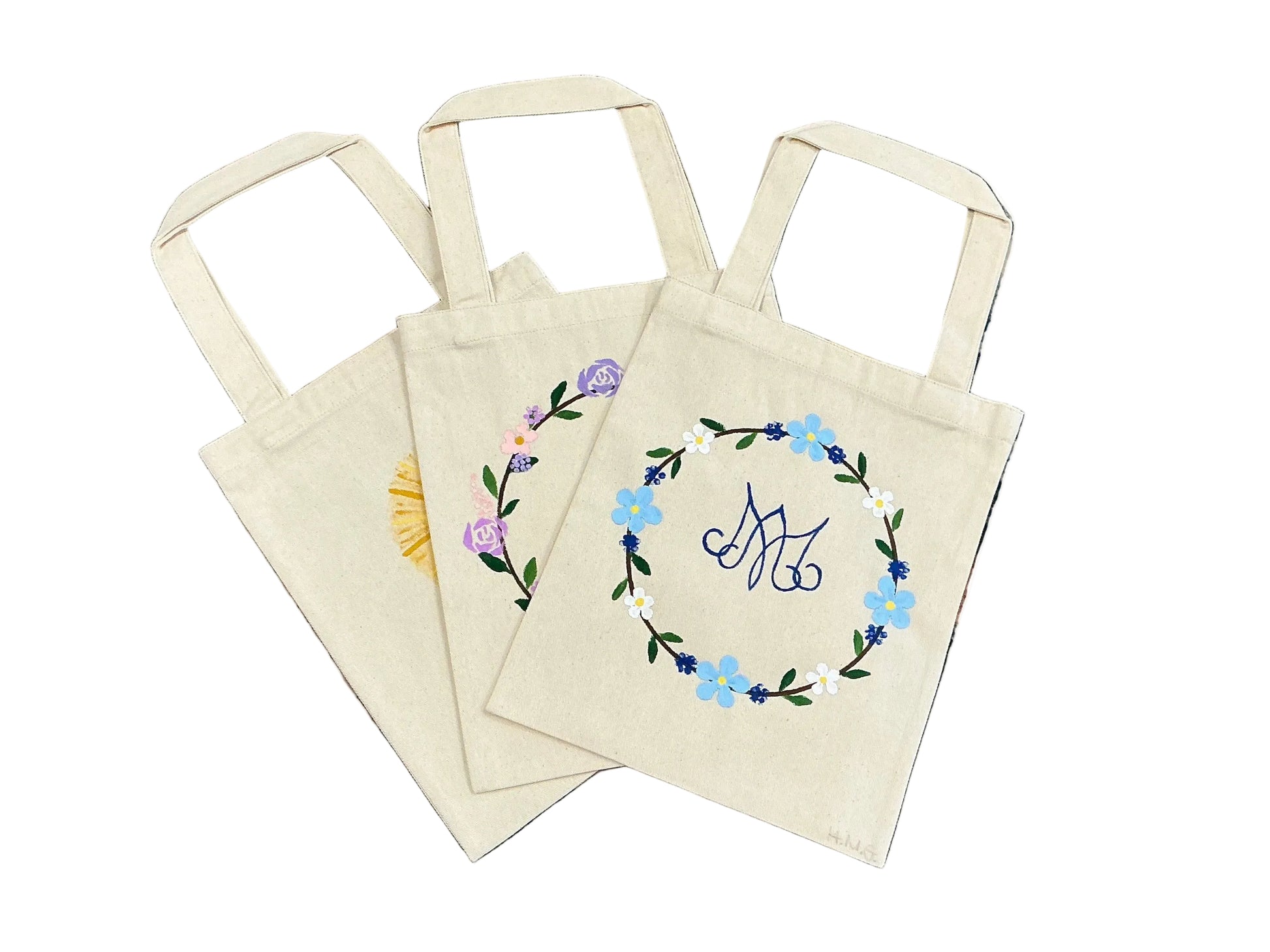 Set of tote bags with floral designs on a textured surface.