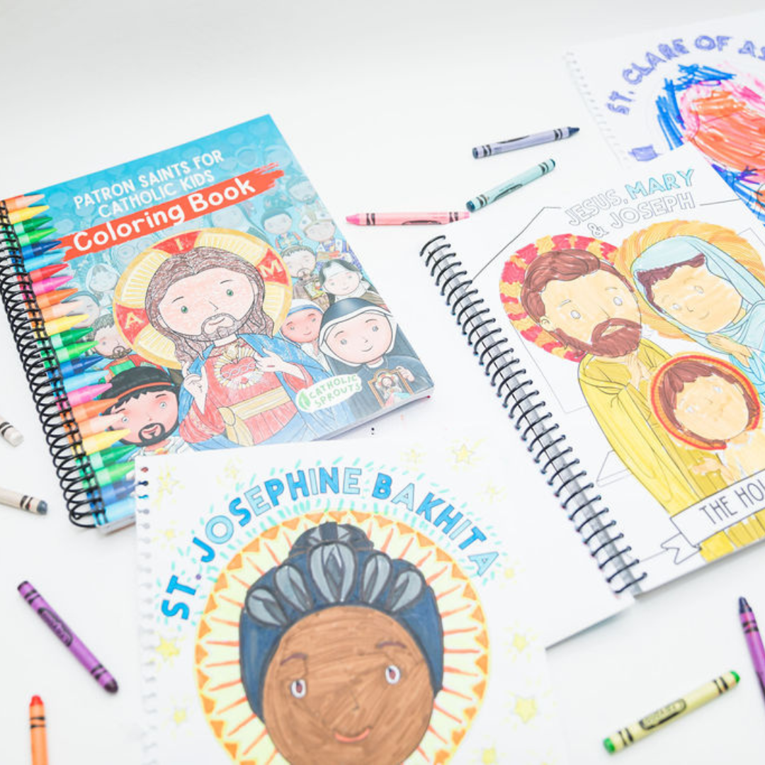 Coloring books with religious illustrations and crayons on a white surface