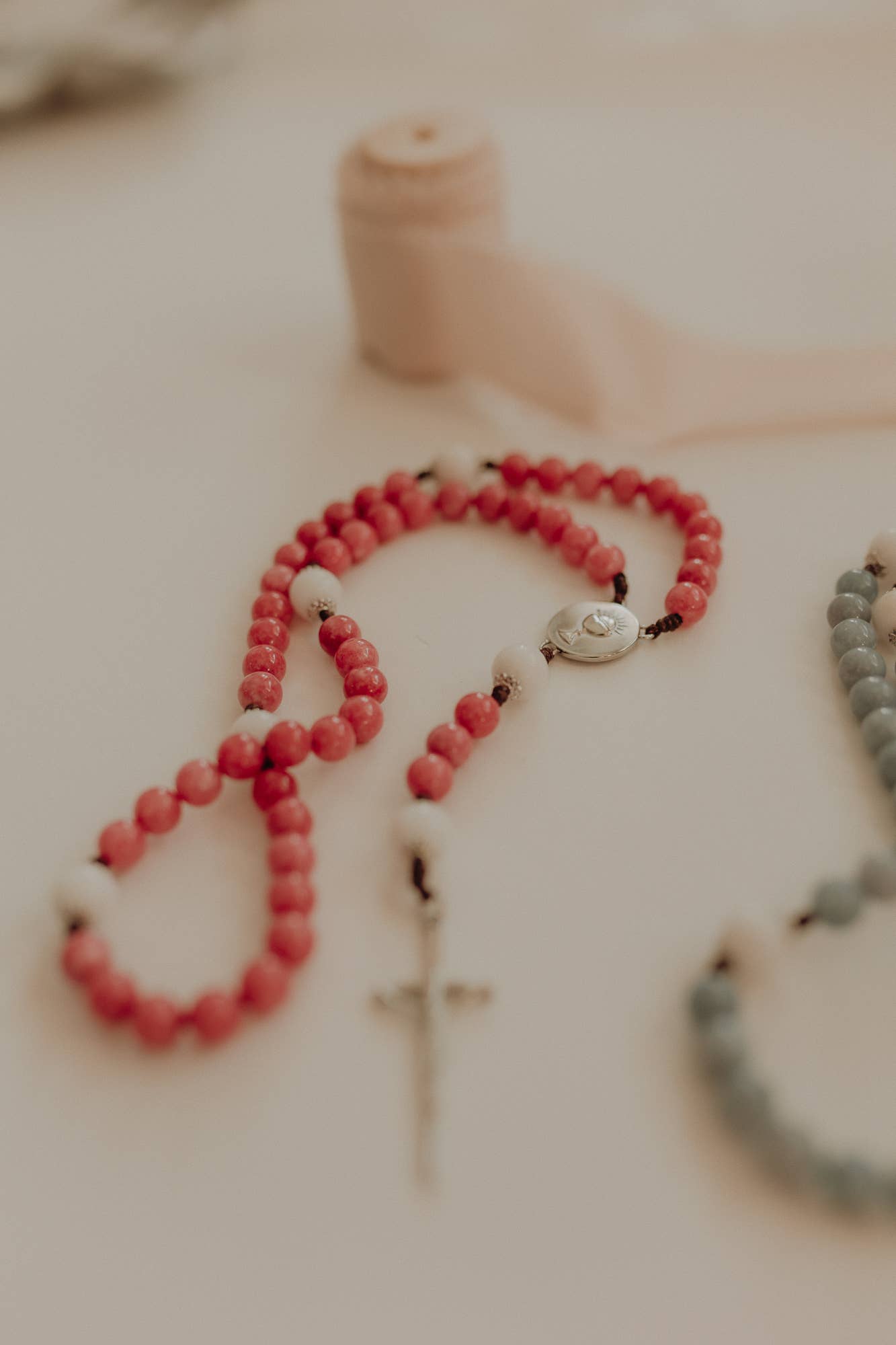 Pink beaded bracelet on a white surface with a blurred background