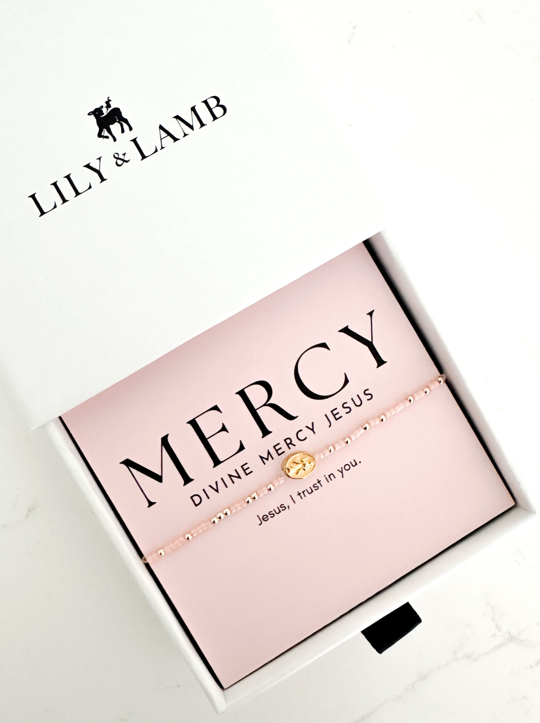 Pink box with 'Mercy' bracelet and Lily & Lamb branding on a white background