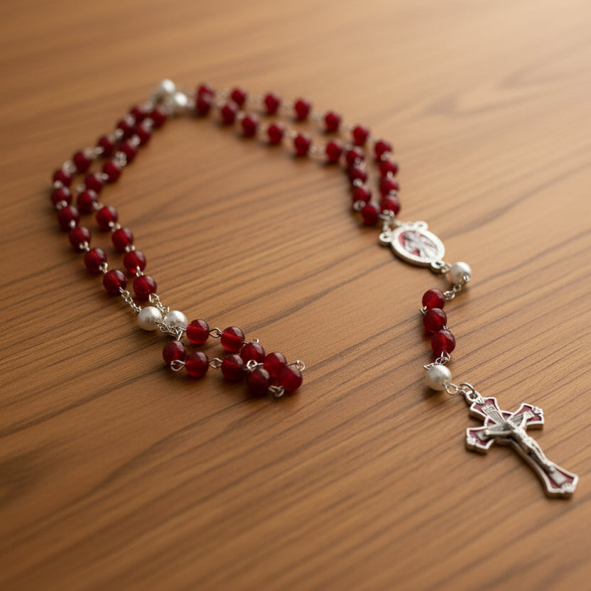 Red and silver rosary on a wooden surface
