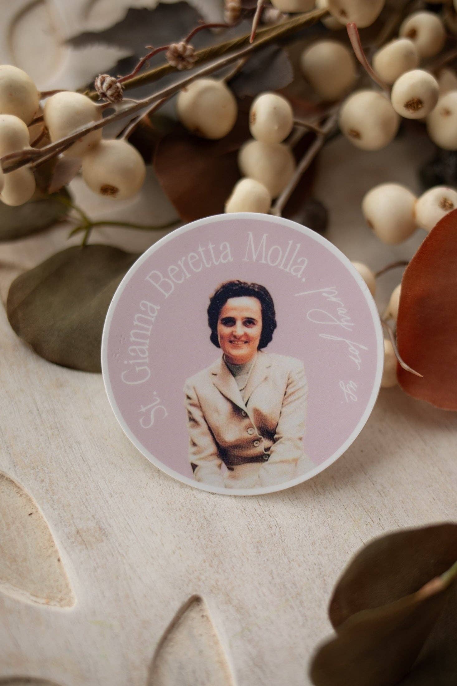 Circular photo of a woman on a decorative plate with white berries and leaves in the background