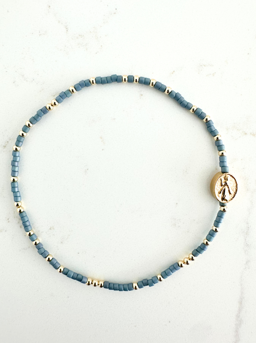 Blue beaded bracelet with gold accents on a white background