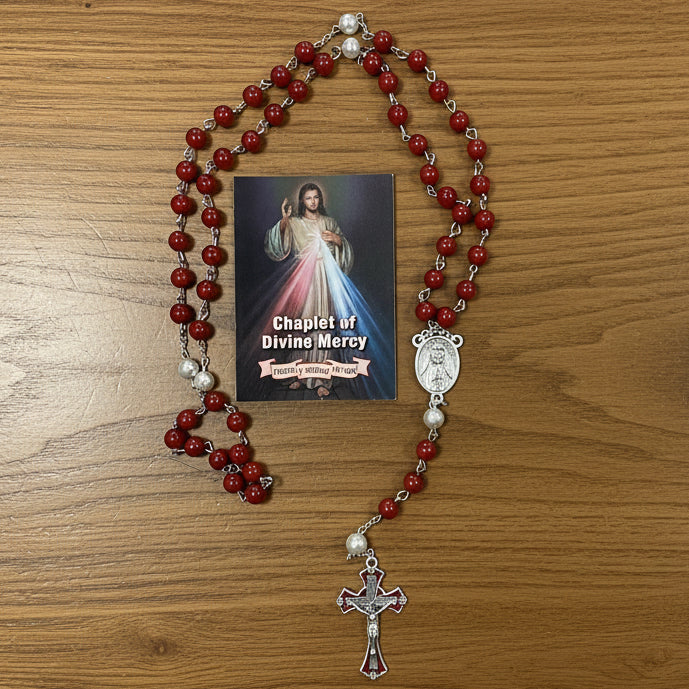 Red rosary with a picture of Jesus on a wooden surface