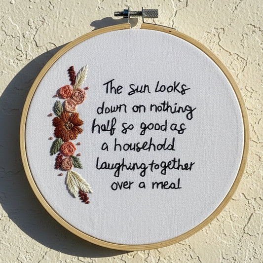 Embroidery hoop with floral design and text on a beige wall