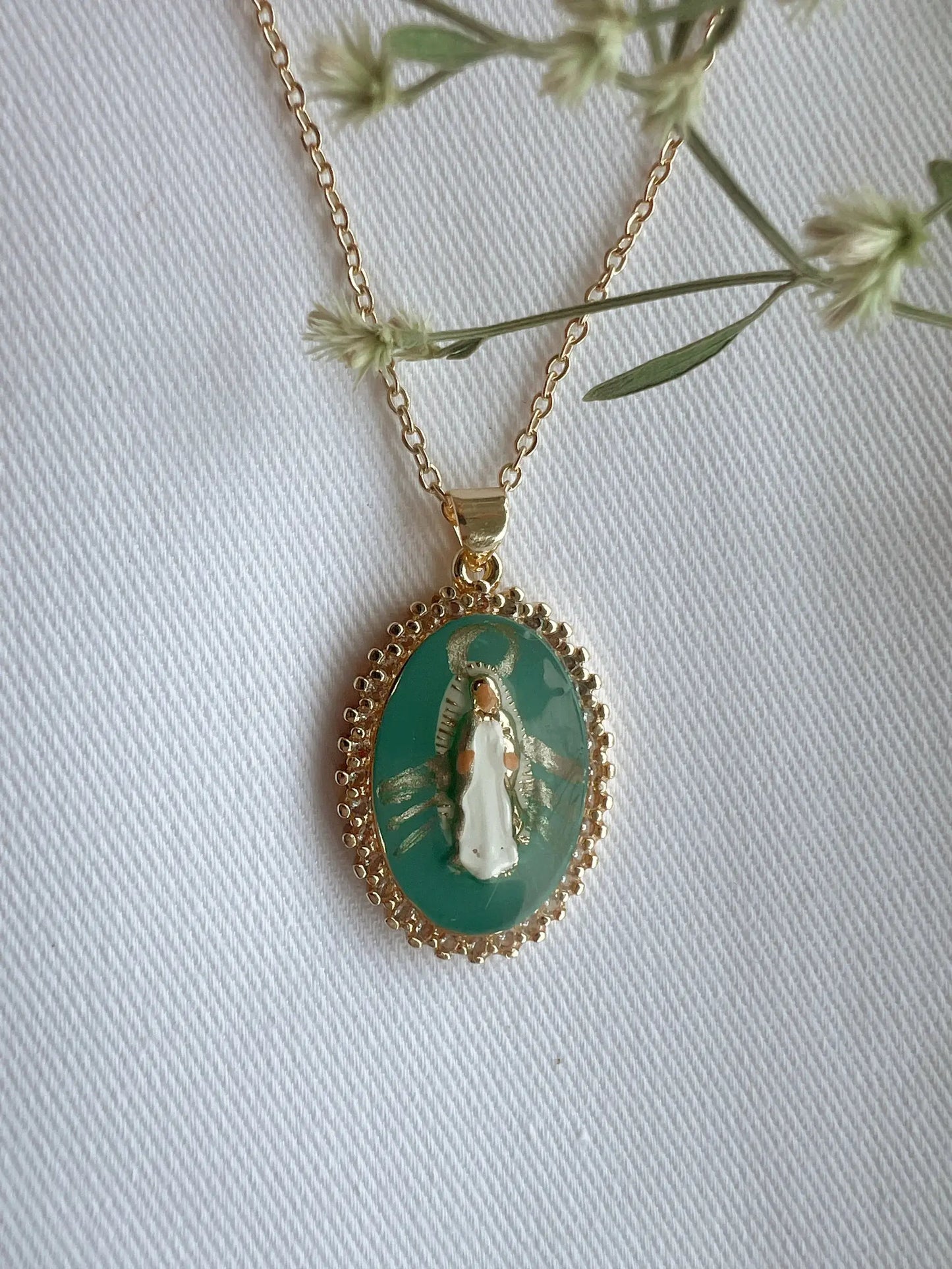 Gold necklace with a pendant featuring a religious icon on a white background