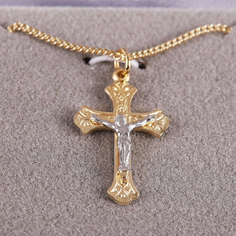 Gold and silver crucifix pendant on a chain against a gray background