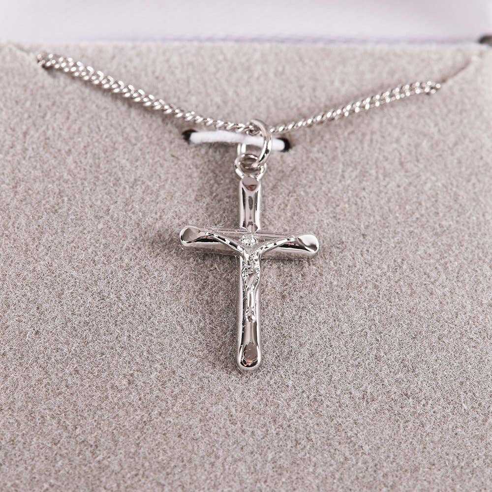 Silver cross pendant necklace on a textured beige surface