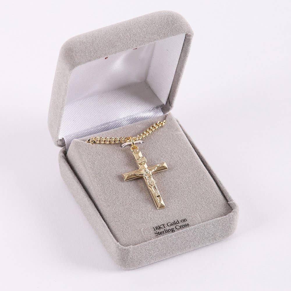 Gold cross necklace in a gray jewelry box on a white background