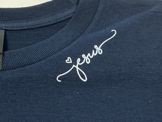 Navy blue shirt with 'Jesus' on it in white on a plain background