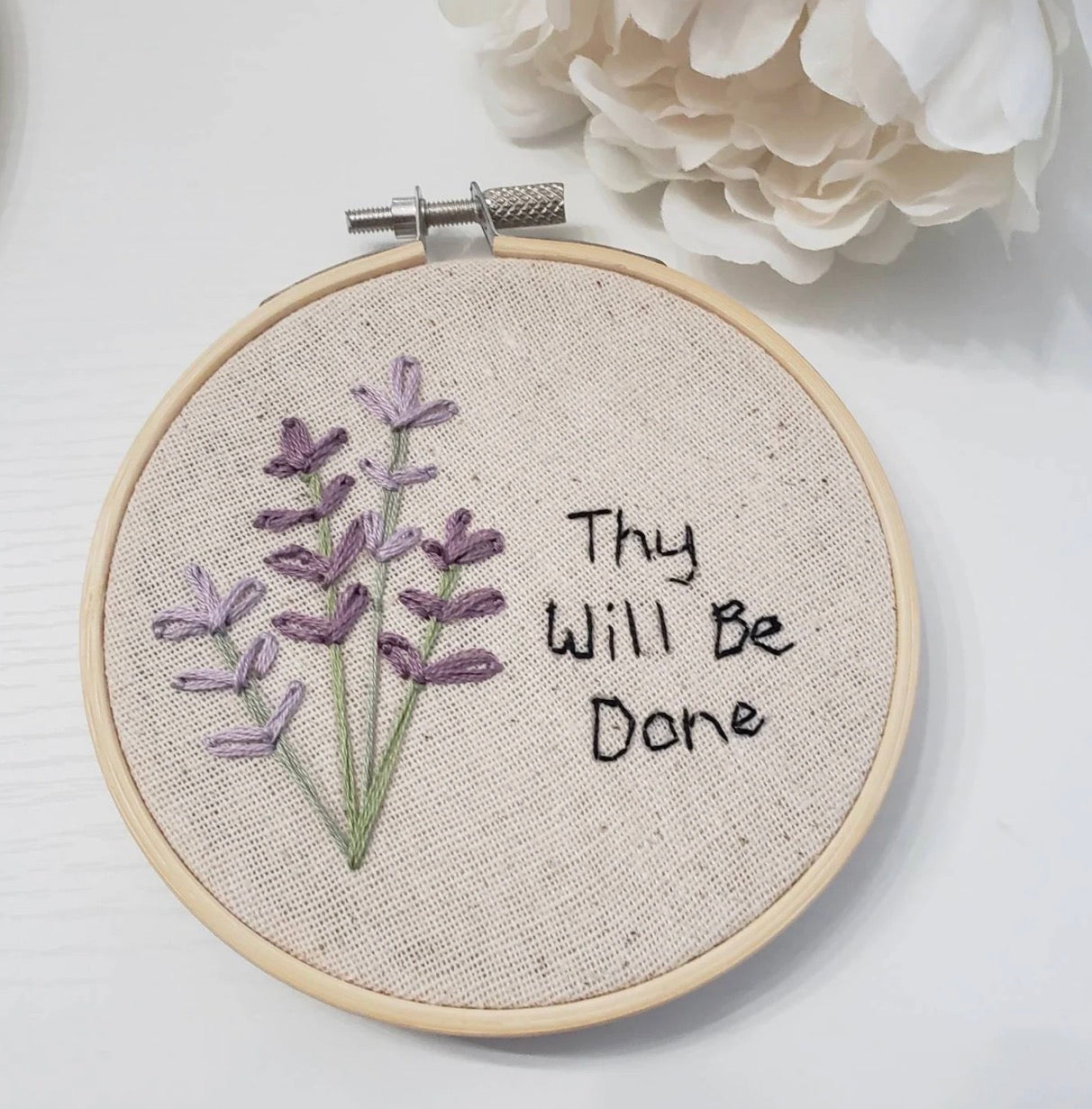 Embroidery hoop with lavender design and 'Thy Will Be Done' text on a white background