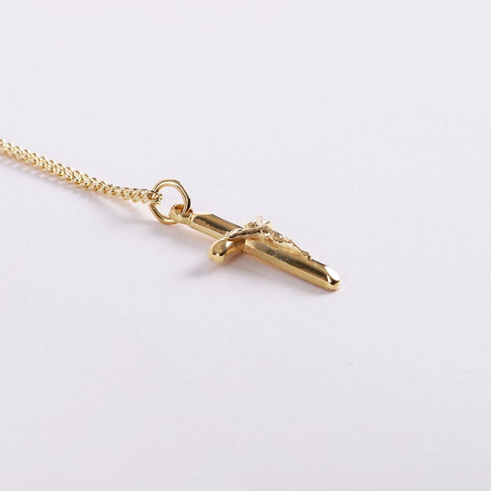 Gold necklace with a cross pendant on a light gray background