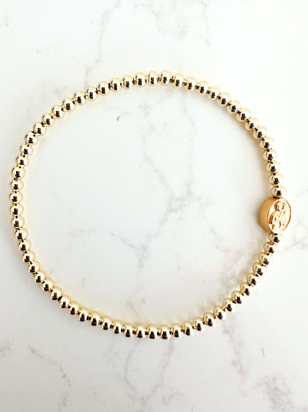 Gold beaded bracelet on a marble surface