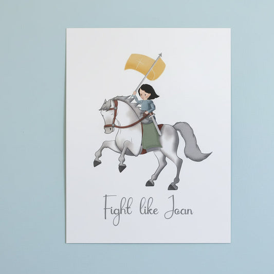 Print with illustration of Joan of Arc on horseback and 'Fight like Joan' text on a white surface.