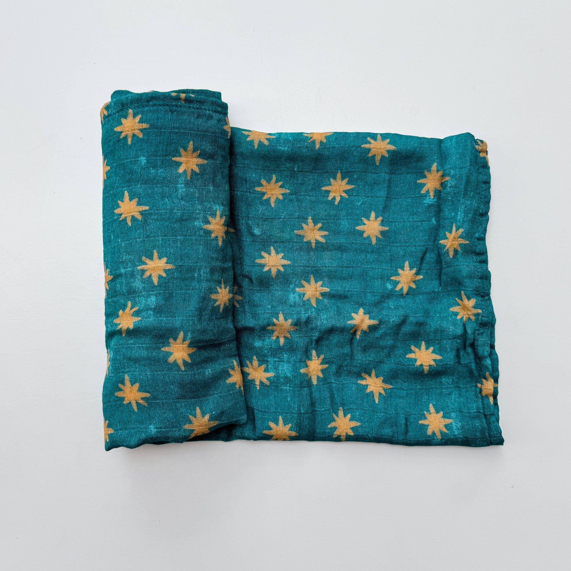 Folded teal fabric with yellow star patterns on a white background