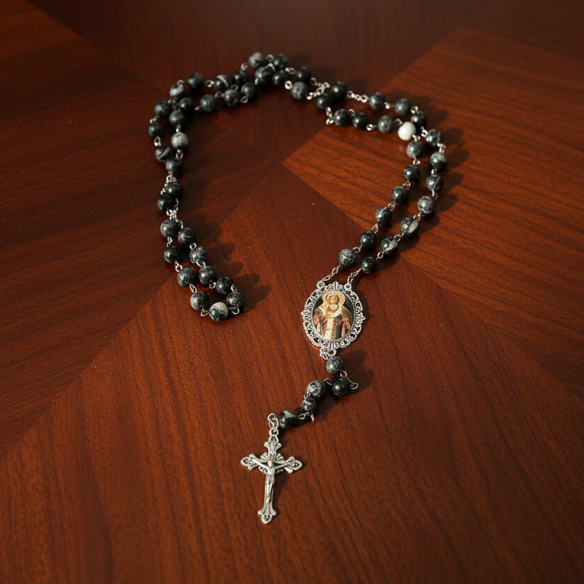 Black rosary with a central pendant on a wooden surface