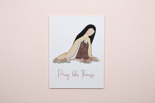 Print with illustration of st. Therese and text 'Pray like Therese' on a white surface.