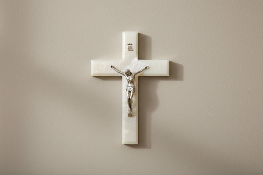 Wall-mounted crucifix with Jesus Christ figure on a beige wall