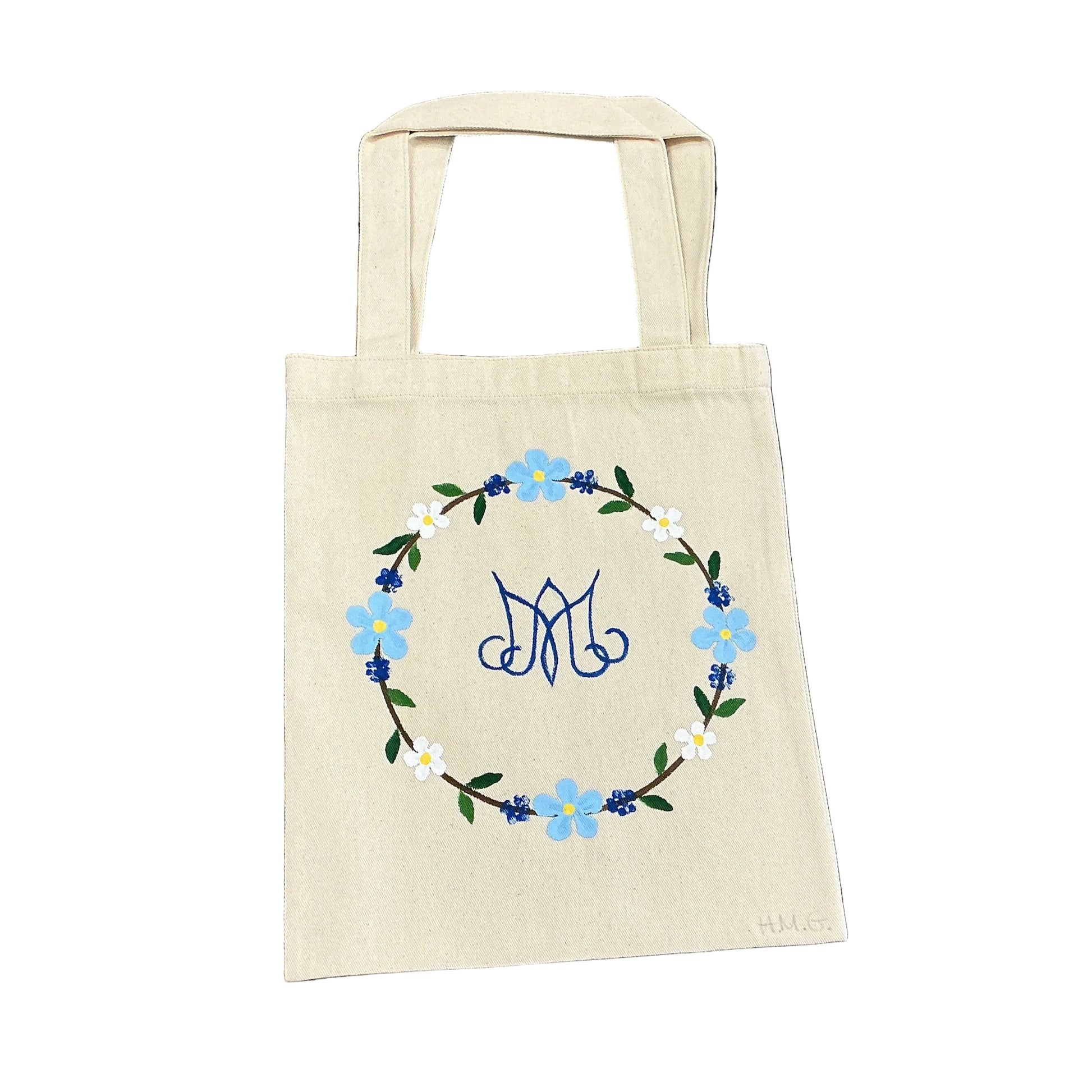 Beige tote bag with floral design on a floral-patterned fabric background