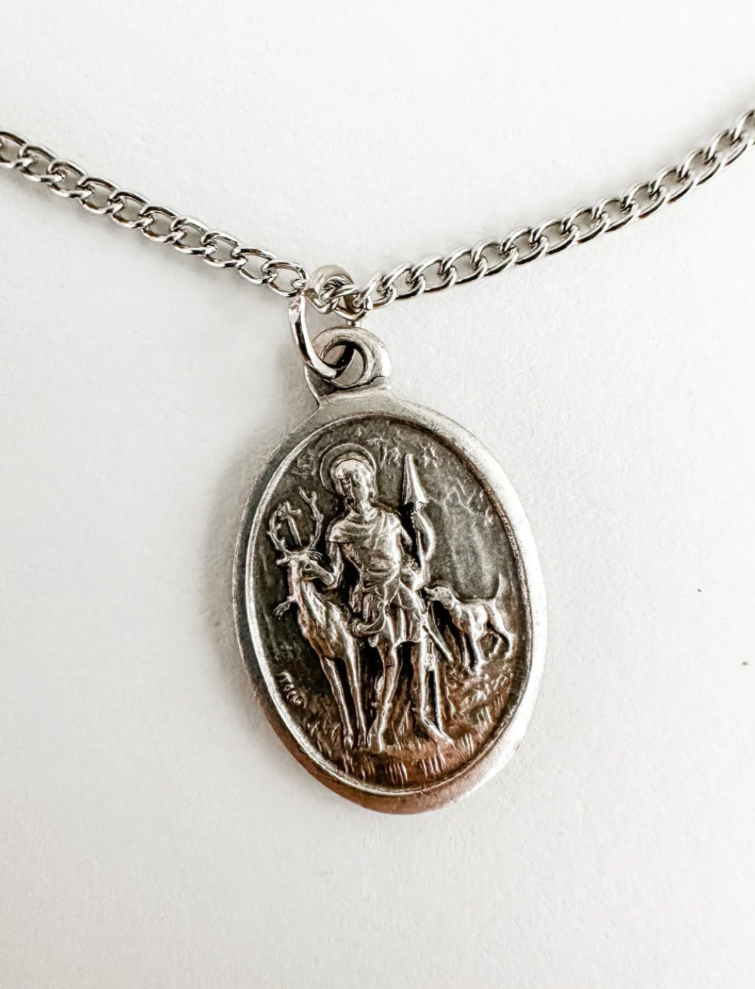 Silver pendant necklace with an engraved design on a white background