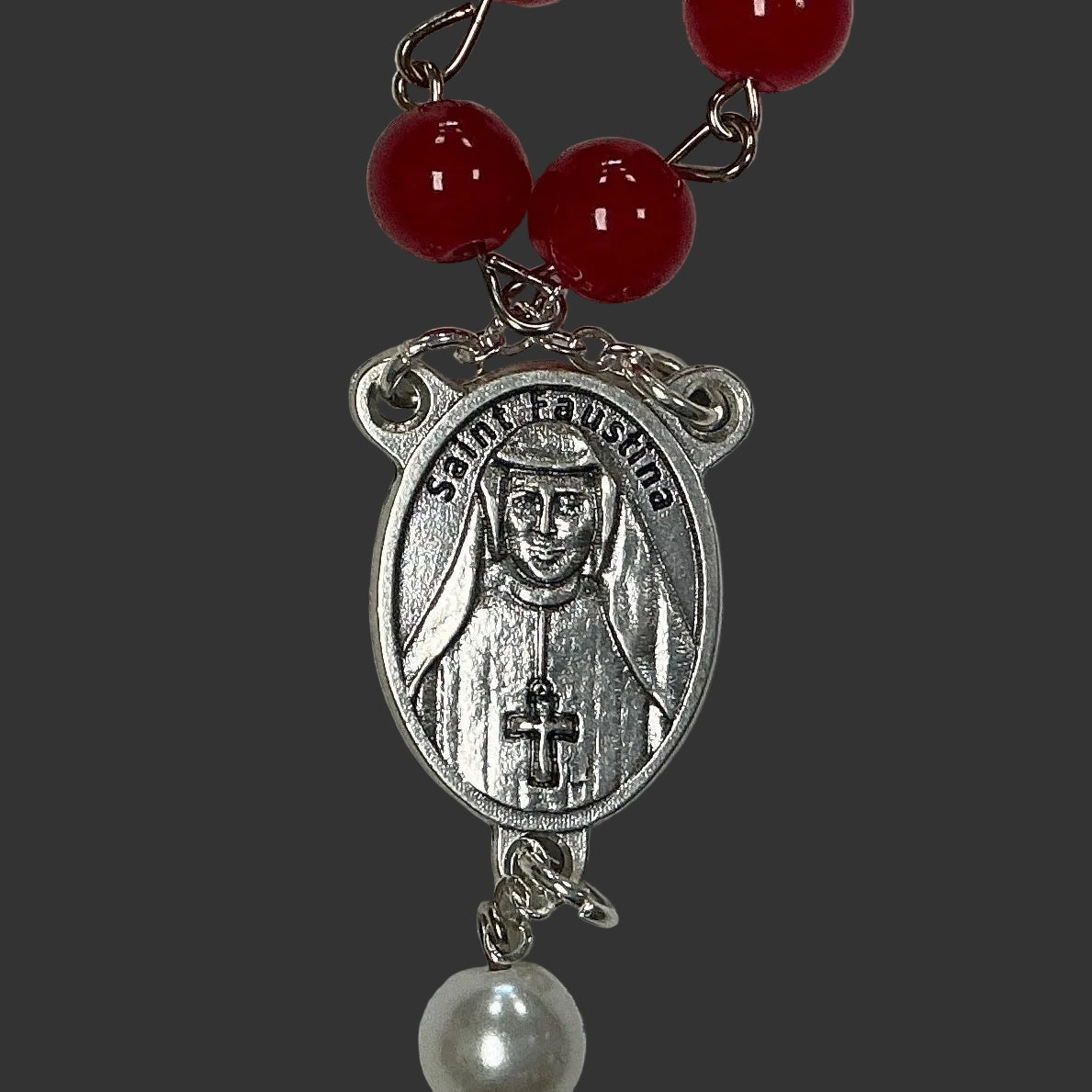 Silver pendant with a face design and red beads on a gray background