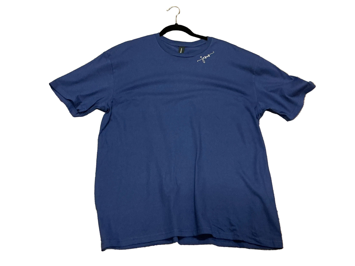 Navy blue t-shirt with “Jesus” written by shoulder on white background 