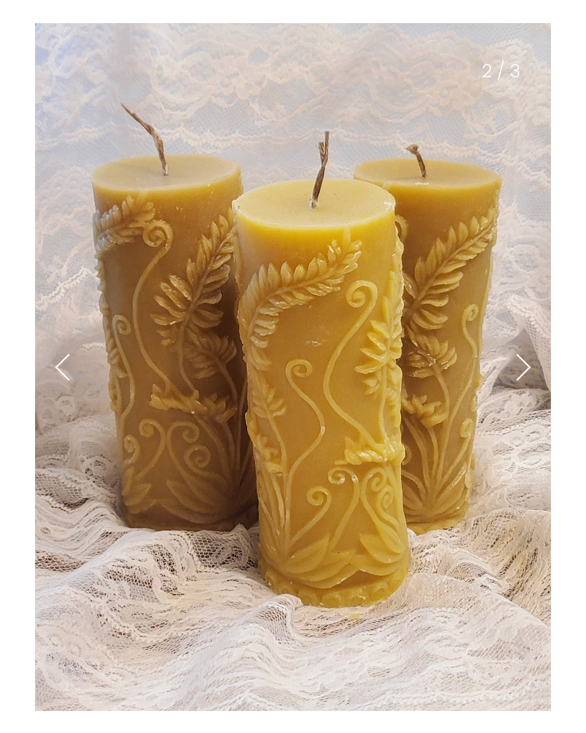 Three beeswax candles with intricate designs on a textured surface