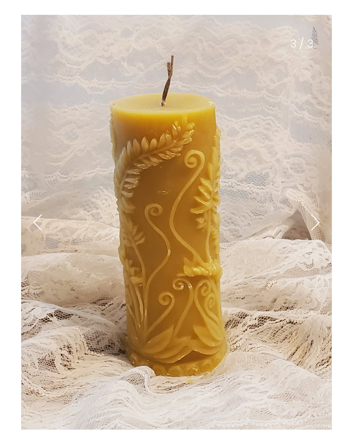 Beeswax fern candle with intricate design on a textured white background