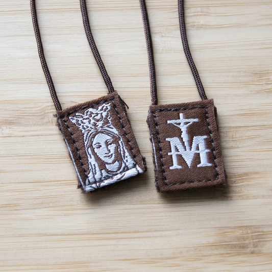 Scapular with religious symbols on a light wood surface