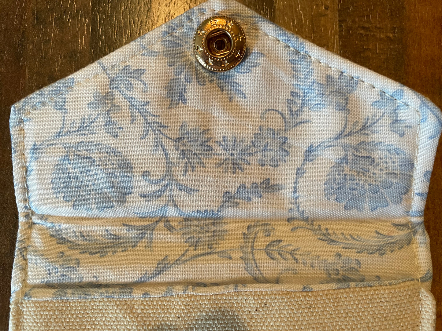 Floral patterned fabric with a gold button on a wooden surface