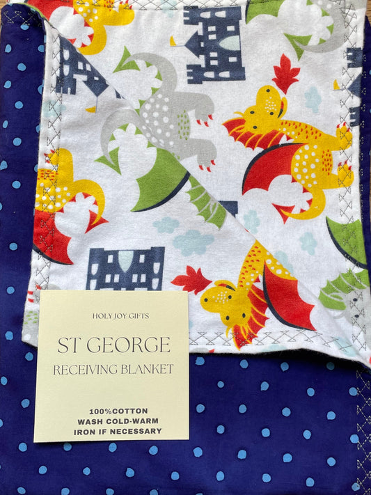 Folded baby blanket with animal pattern and blue border on a wooden surface, featuring a 'St. George' label.