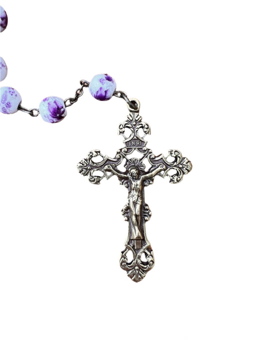 Rosary with purple beads and a detailed cross on a white background