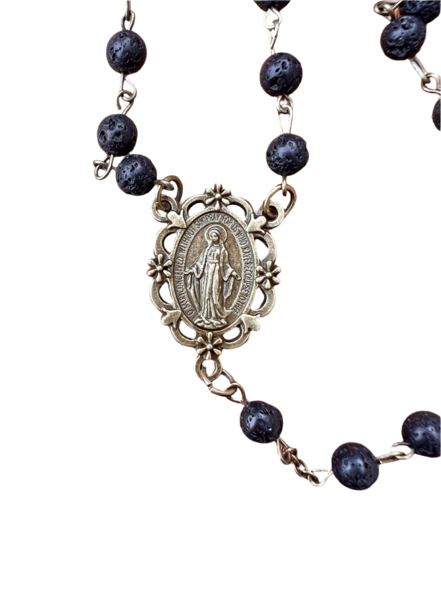 Rosary with black beads and a miraculous medal on a white background