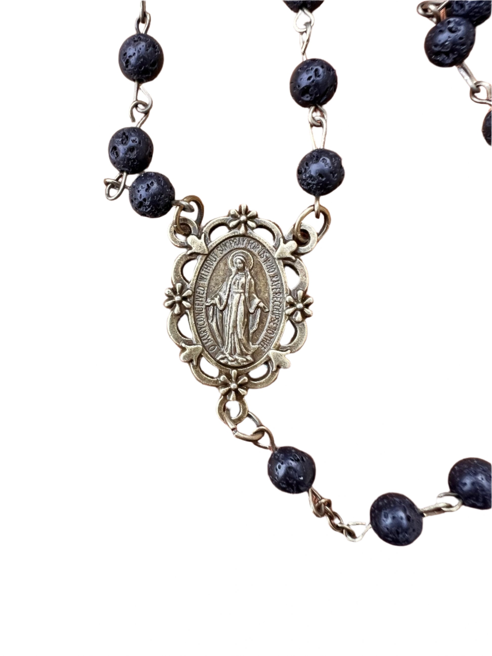 Rosary with black beads and a miraculous medal on a white background