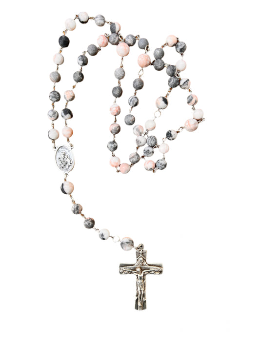 Rosary with multicolored beads and a silver cross on a wooden surface