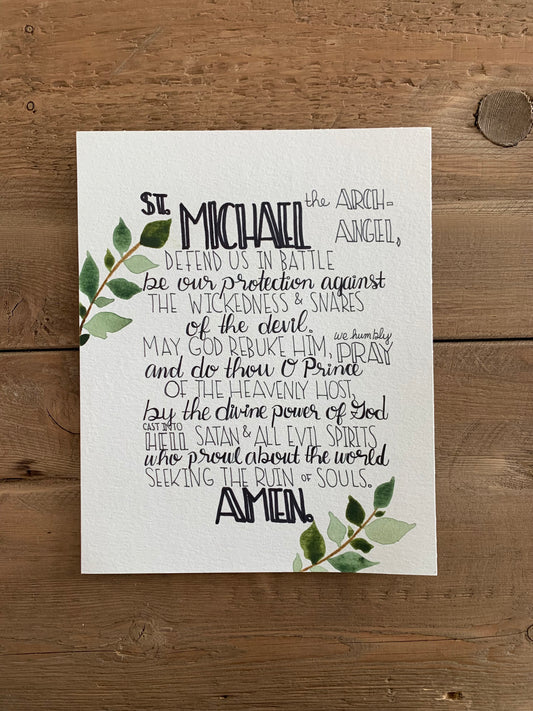 Print with St. Michael prayer on a wooden surface