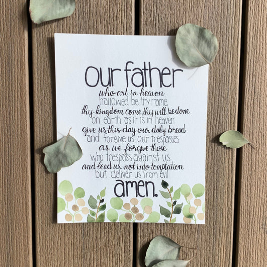 White card with printed text and green leaf decorations on a wooden surface