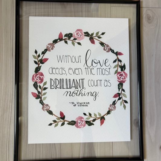 Framed print with floral design and text on a wooden surface
